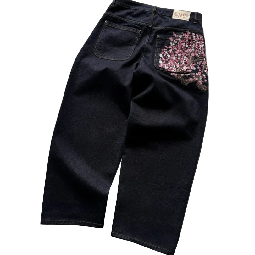 Black jeans with floral embellishments on a concrete surface