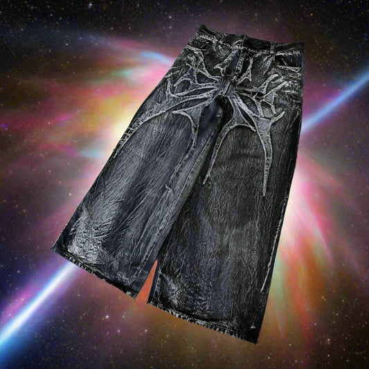 Black leather pants with intricate white designs on a gray concrete surface