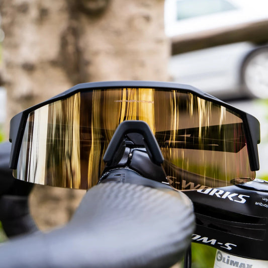 Close-up of a motorcycle visor with 'OWE' branding, held by a gloved hand against a blurred natural background.