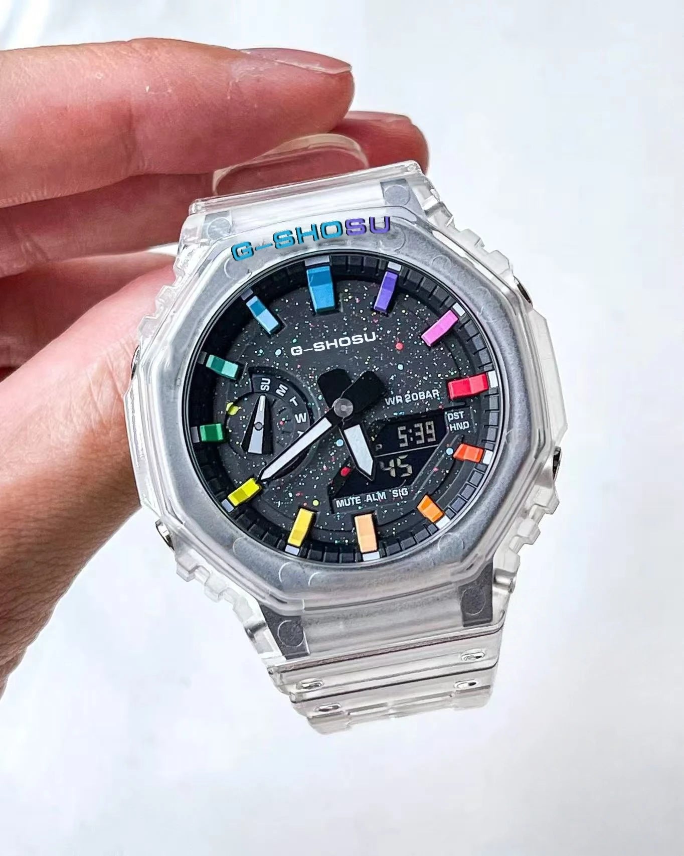 G-Shock watch with colorful face held by a hand on a white background