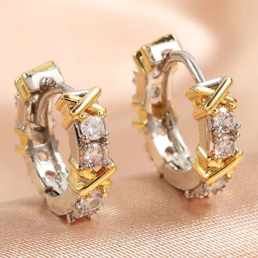 Gold and silver hoop earrings with embedded stones on a soft pink background