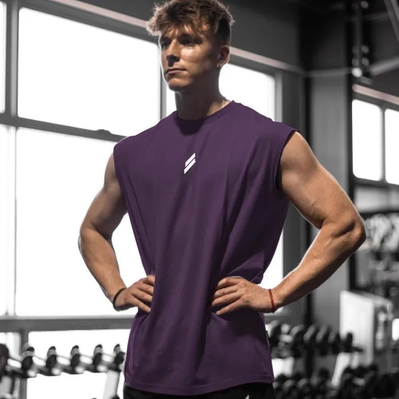 Man wearing a purple sleeveless shirt with a logo in a gym setting

