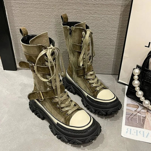 Pair of green high-top boots with white soles on a gray surface.