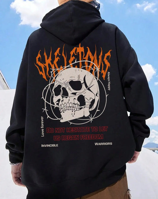 Person wearing a black hoodie with a skull design and text on the back, standing against a blue sky.
