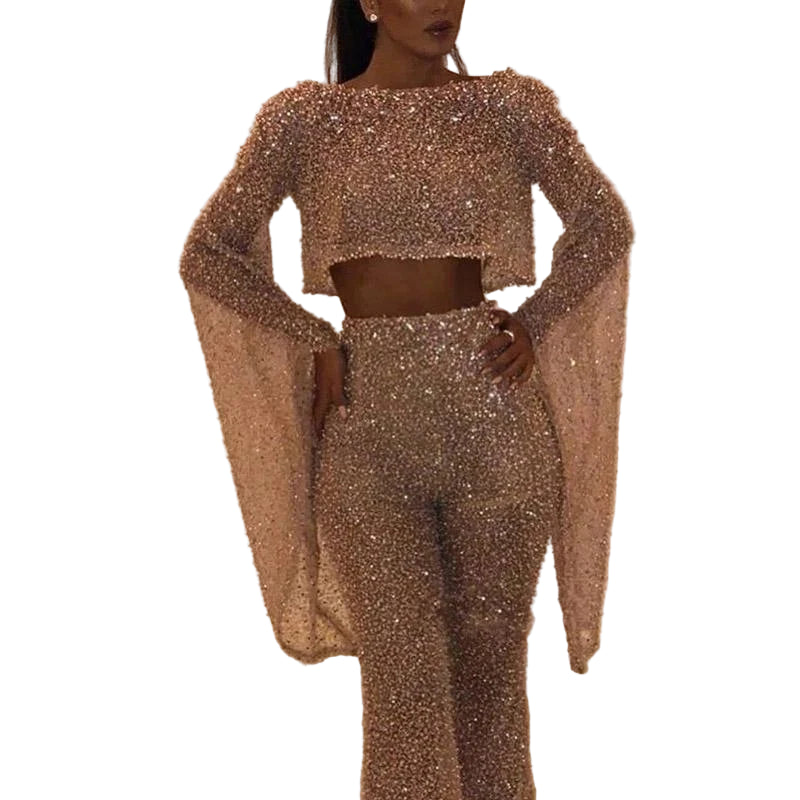 Person wearing a sparkling two-piece outfit with long sleeves on a neutral background