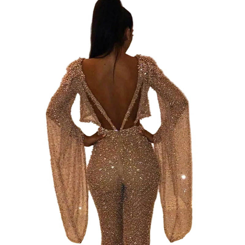 Person wearing a sparkly, long-sleeve jumpsuit with a blurred background