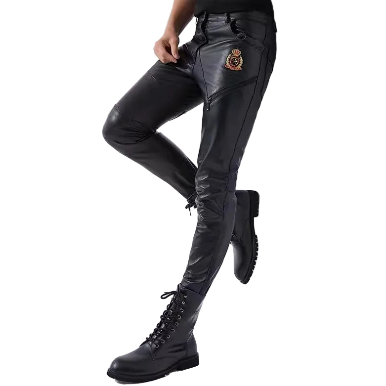 Person wearing black leather pants with a patch and black boots on a white background