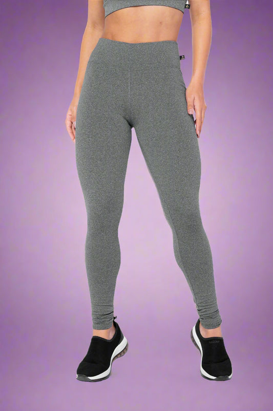 Person wearing gray leggings and black athletic shoes on a white background