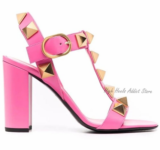 Pink high-heeled sandals with gold studded details on a white background