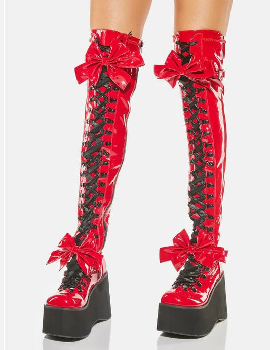 Red platform boots with black laces and bows on a white background
