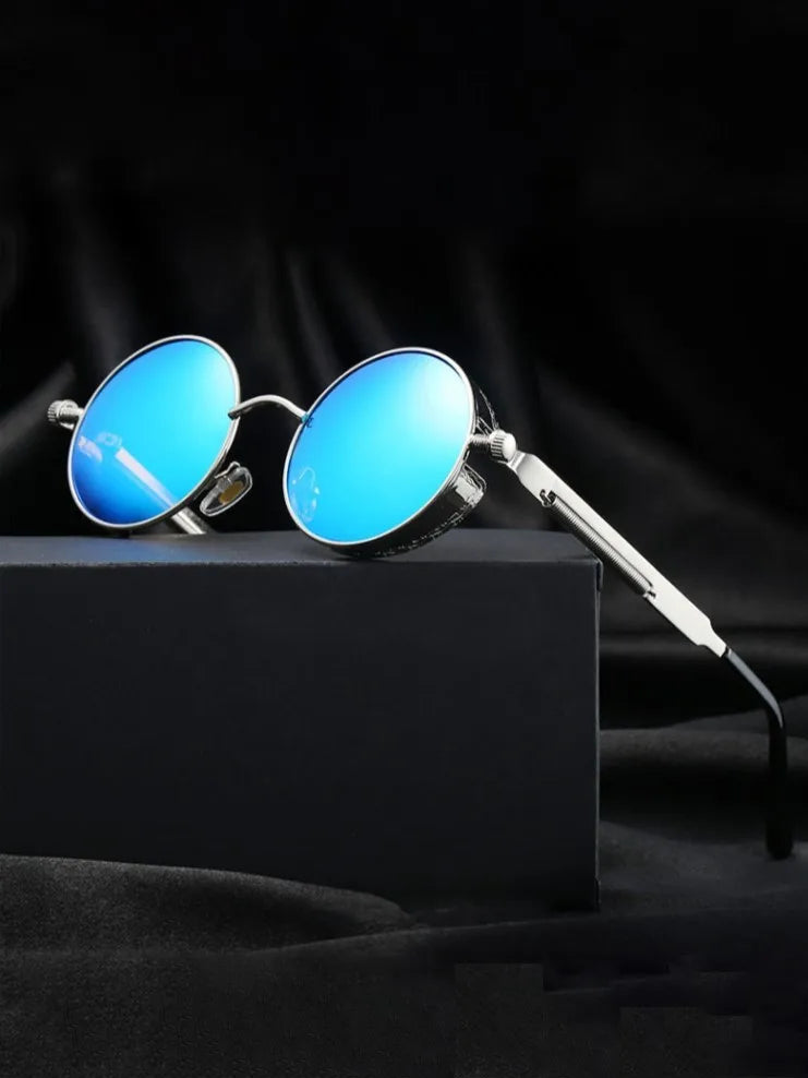 Round blue sunglasses with silver frames on a black box against a black background