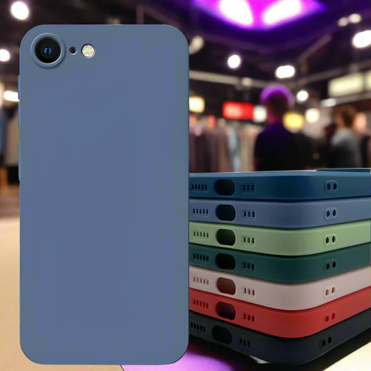 Stack of phone cases in various colors on a white surface with a blurred green plant in the background.