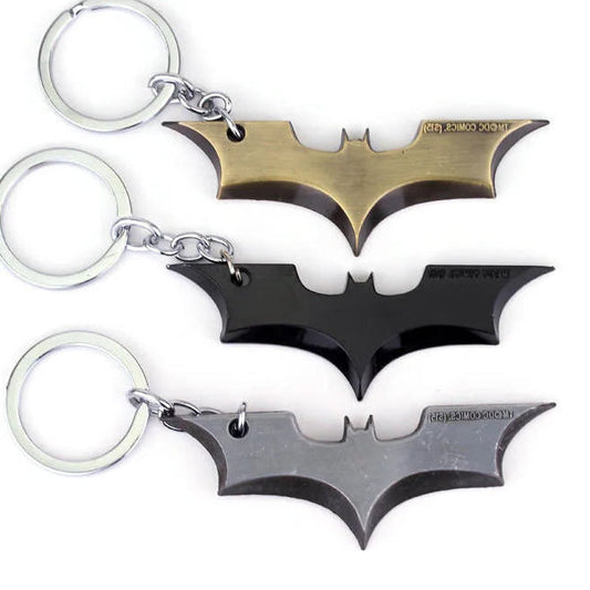 Three bat-shaped keychains in gold, black, and silver on a white background