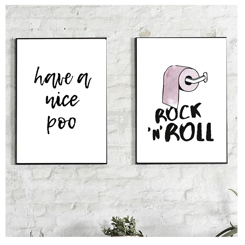 Two framed prints on a white brick wall with humorous text and a toilet paper roll illustration.