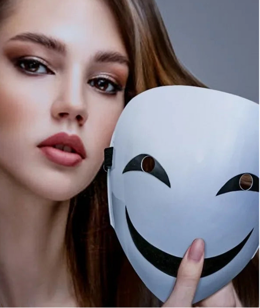 Woman holding a white mask with a smiley face design against a gray background