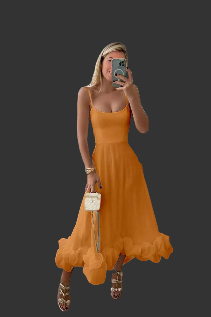 Woman in an orange dress taking a mirror selfie in a bright room.